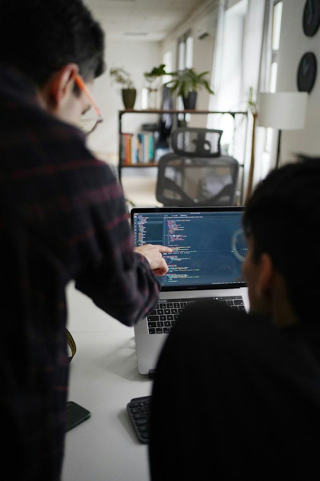 Two developers reviewing code together on a laptop